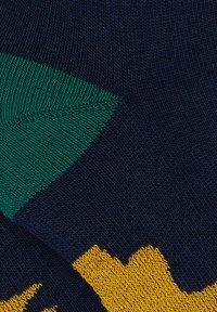 Tessuto lavorato a maglia multicolore con sezioni blu navy, verde e giallo, caratterizzato da un design testurizzato. Finitura liscia, con motivi geometrici visibili.