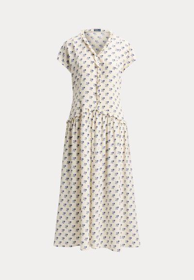Kermanvärinen lyhythihainen mekko sinisellä kukkakuviolla, napitettu edestä, röyhelöyksityiskohdilla ja kerätty midi-lenkkinen hame.