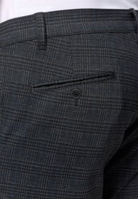 Pantalones grises con un diseño de cuadros, que cuentan con un bolsillo trasero y un detalle de un solo botón negro. El material tiene un acabado texturizado.