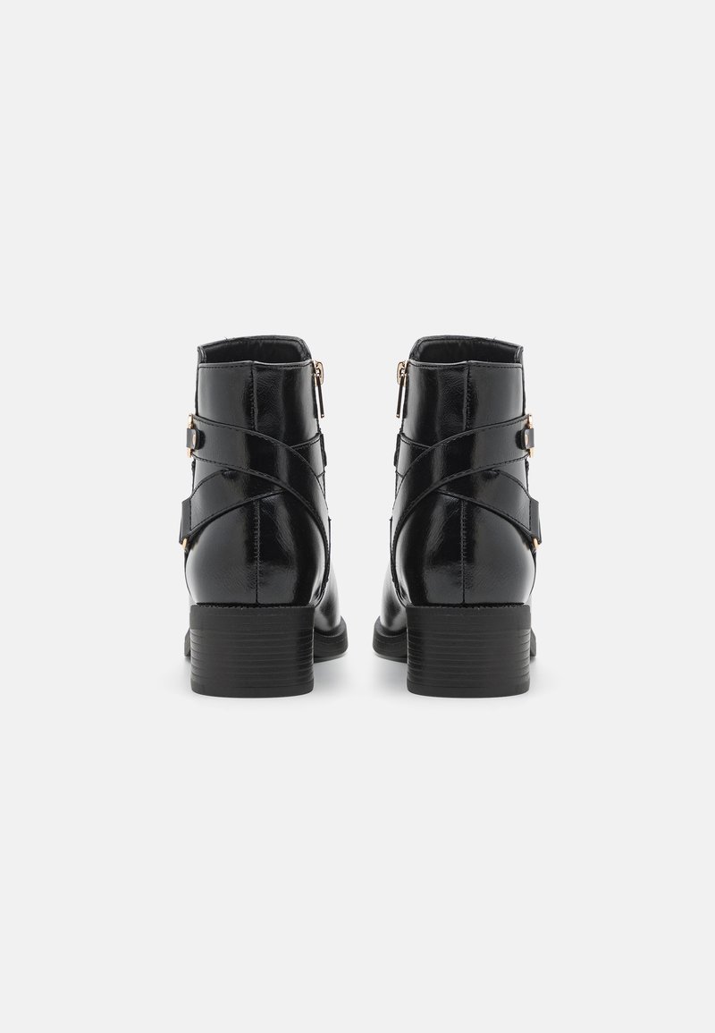 Botas de tobillo de cuero negro con un acabado brillante, que presentan dobles cremalleras y correas decorativas entrelazadas en los lados. Tacones bajos apilados.