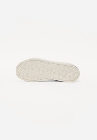 Fehér sneaker talp, textúrált tapadási mintával, kerek orral és sima élekkel. Minimalista és letisztult esztétikával megtervezve.