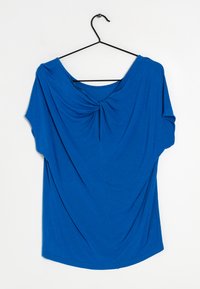Modrý krátký rukáv top vystavený na černém ramínku; má volný střih s uzlovým designem vpředu a hladký, jemný materiál.