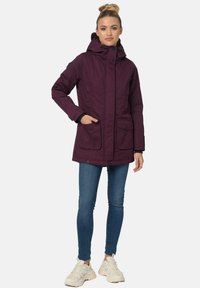 Purple hooded parka jacket with a buttoned front, two front pockets, and adjustable cuffs, paired with blue jeans and white sneakers.
