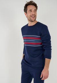 Marineblauwe sweatshirt met een ronde halslijn, voorzien van horizontale strepen in rood, wit en blauw over de borst. Zachte stof, casual pasvorm.