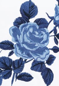 Rosa bordada azul con hojas detalladas sobre un fondo de tela blanca, mostrando un intrincado bordado y sombreado.