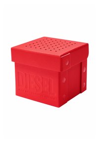 Conteneur carré rouge de marque Diesel avec couvercle perforé et texture en relief sur fond blanc.