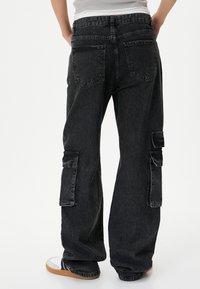 Zwarte denim cargobroek met wijde pijpen, twee cargozakken op de bovenbenen en klassieke achterzakken. Heeft een vervaagde textuur en een casual pasvorm.