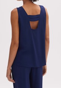 Granatowa bezrękawnik z dekoltem w kształcie litery U na plecach, wykonany z miękkiego materiału, z prostymi liniami i luźnym krojem.