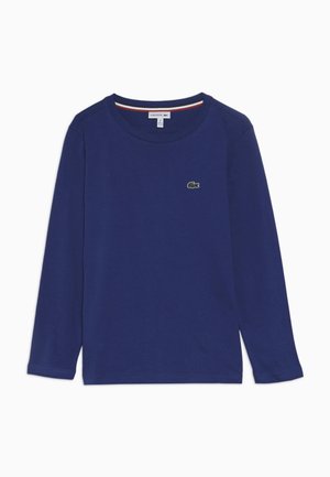 T-shirt bleu marine à manches longues col rond avec petit logo crocodile vert sur la poitrine gauche et bordure rouge-blanc-bleu à l’intérieur du col.