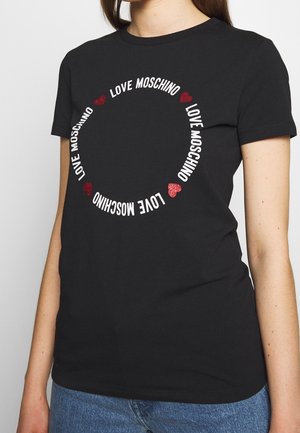 Schwarzes T-Shirt mit kreisförmigem "LOVE MOSCHINO"-Schriftzug in Weiß, akzentuiert mit roten Glitzerherzen. Kurze Ärmel und Rundhalsausschnitt.