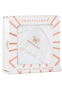 Transparante edelsteen gezichts-gua sha in een witte doos met een geometrisch ontwerp. De doos heeft roségouden accenten en de merknaam "CRYSTALLOVE".