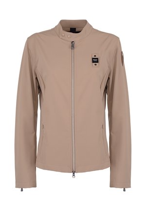 Veste beige zippée avec col montant, deux poches latérales, boutons-pression au col et petite écusson noir avec logo sur la poitrine et le bras.