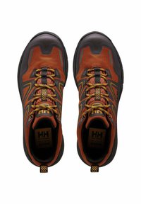 Zapatos de senderismo en marrón y negro con parte superior de malla, suela de goma, acentos amarillos y cordones texturizados. Presenta un cuello acolchado y detalles del logo.