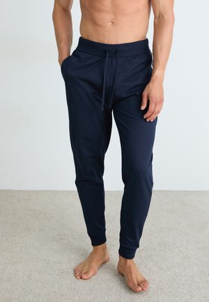 Navy jogger pants made of a soft material with an elastic waistband and drawstring, featuring tapered legs and side pockets.