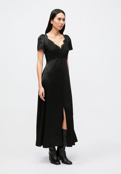 Lange zwarte jurk met kanten lijfje, pofmouwen, V-hals en knoopsluiting aan de voorkant. Voorzien van een split aan de zijkant en een gladde satijnen textuur.