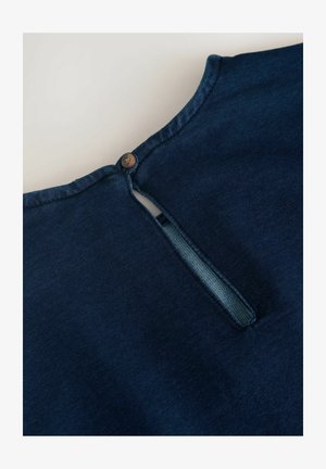 Ciemnoniebieski kołnierzyk z otworem w kształcie klucza, z brązowym zapięciem na guzik. Gładka faktura tkaniny z starannymi detalami przeszycia.