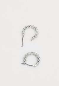 Stříbrné kruhové náušnice s korálkovým designem. Kulaté tvary mají hladký metalický povrch a zakřivené drátové zapínání pro bezpečné nošení.