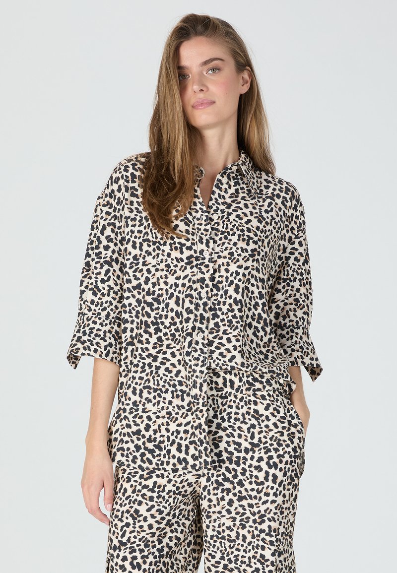 Leopard print shirt made of lightweight fabric, featuring a button-up front, collar, and loose sleeves, paired with matching pants.