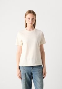 T-shirt a maniche corte di colore crema chiaro, realizzato in morbido cotone. Caratterizzato da un collo rotondo e un discreto logo sul petto. Vestibilità casual.