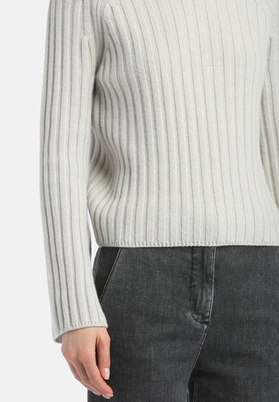 Pullover bianco a coste con maniche lunghe, caratterizzato da un motivo testurizzato e orlo corto, abbinato a jeans grigio scuro.
