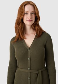 Rippstrick Cardigan in olivgrün mit V-Ausschnitt, Knopfverschluss und passendem Gürtel in der Taille, ausgestattet mit langen Ärmeln und strukturiertem Stoff.