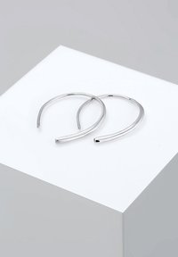Aros de plata con un diseño liso y minimalista, que presentan una forma delgada y alargada con un acabado pulido.