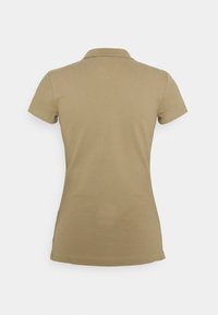 Polo beige à manches courtes avec col, vu de dos sur un fond clair uni.