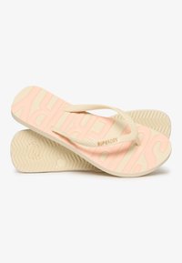Infradito con una soletta texturizzata di un rosa chiaro, con il logo "SUPERDRY" in rilievo, cinturini in gomma beige e suola a zigzag.