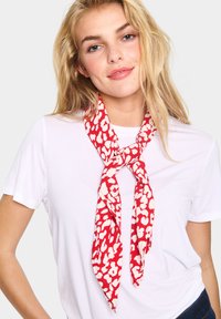 Eșarfă cu model roșu și crem legat�ă în jurul gâtului, realizată dintr-un material ușor, cu o textură netedă și un design cu print leopard.