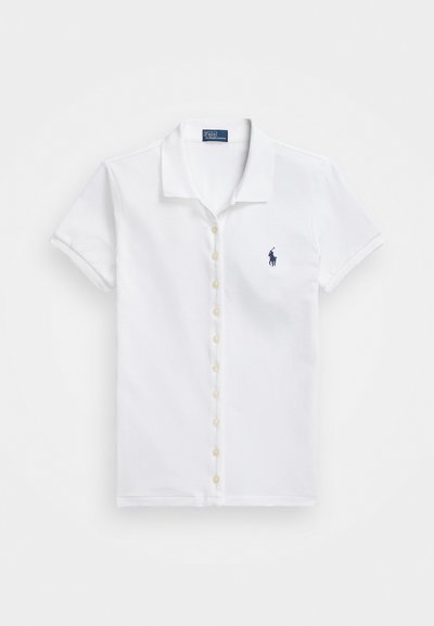 Bela majica s kratkimi rokavi iz bombaža, z gumbom na sprednji strani in majhnim modrim logotipom na levem prsnem delu.