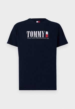 Marineblauwe katoenen t-shirt met korte mouwen, voorzien van een groot wit "TOMMY" logo en een klein ontwerp van de Franse vlag. Tekst: "TOMMY JEANS WORLDWIDE SINCE 1985."