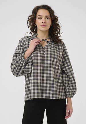Black and white plaid blouse with long balloon sleeves, a scooped neckline, and tie detail at the neck. Features button accents.