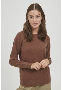 Ruskea neulepusero, jossa on pitkät hihat, pyöreä pääntie ja ribbaavat hihansuut. Kangas näyttää pehmeältä ja hieman pörröiseltä, ja siinä on rento istuvuus.