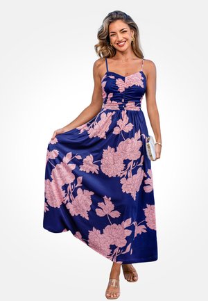 Vestito lungo a fiori con corpetto aderente, tessuto blu navy e grandi motivi di peonie rosa. Caratterizzato da spalline sottili e gonna fluente. Sandali trasparenti.