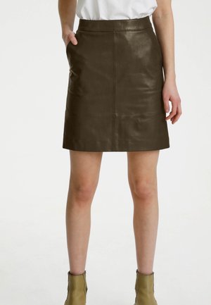 Jupe en cuir marron avec une coupe droite, présentant une texture lisse et deux poches latérales. Elle possède des coutures discrètes et une ceinture.