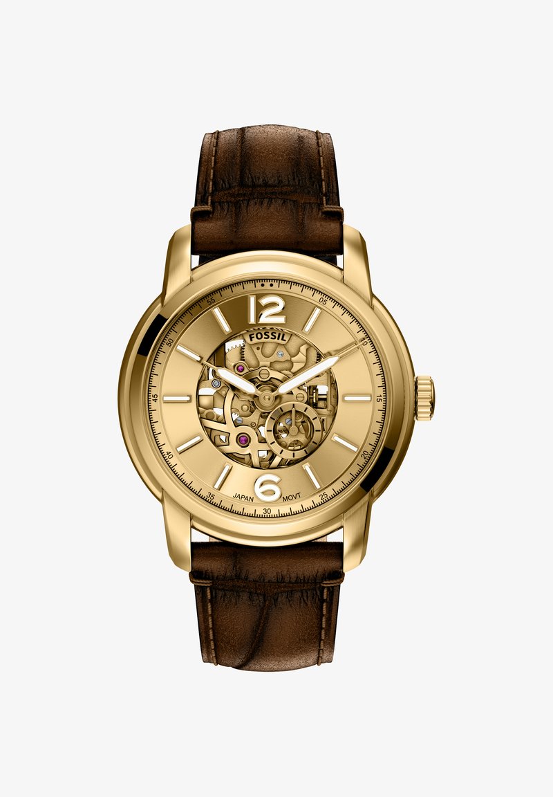 Montre de couleur or avec un cadran transparent, dévoilant le mouvement mécanique. Bracelet en cuir marron avec finition texturée. Présente de grands marqueurs d'heure.