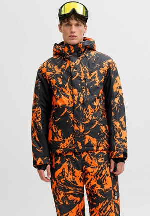 Skijack en -broek set met een zwarte basis en gedurfde oranje abstracte patronen. Gemaakt van waterproof materiaal met een gewatteerd ontwerp.