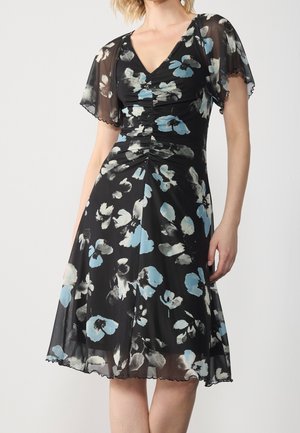 Sort knælængde kjole med blå og hvide blomsterprint, gennemsigtige korte fløjlsærmer, V-udskæring og rynket overdel.