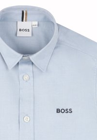 Camicia azzurra chiara con colletto realizzata in tessuto morbido, con chiusura a bottoni, logo ricamato "BOSS" e dettagli di cucitura sottili.