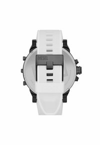 Cinturino in silicone bianco con fibbia in metallo nero incisa "DIESEL," attaccato a un cronografo con cassa nera e argento vista da dietro.