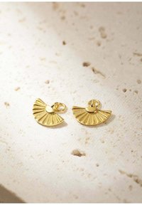 Pendientes en forma de abanico dorados con un diseño texturizado que presenta estrías y un centro liso. Expuestos sobre una superficie neutra.