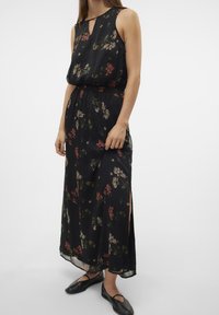 Tmavé květinové maxi šaty s bezrukávovým designem, s výstřihem na klíček a bočními rozparky. Vyrobené z lehkého, splývavého materiálu.
