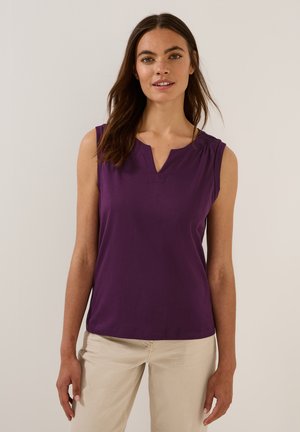 Purple sleeveless top with a V-neck and gathered detailing at the shoulders, made of soft fabric. Paired with light beige pants.