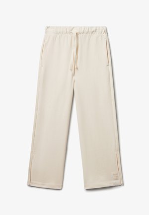 Lichtbeige sweatpants van zacht materiaal, met een elastische tailleband met trekkoord en zijzakken. Kleine tekstdetail op de zoom.