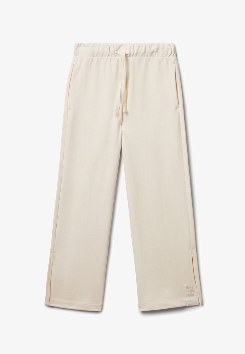 Jasnobeżowe dresy uszyte z miękkiego materiału, z elastycznym paskiem w talii z troczkiem oraz bocznymi kieszeniami. Mały napis na dolnym obszyciu.