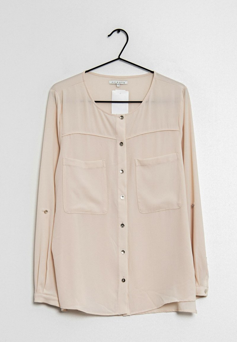 Beige skjorta med knappar i lätt tyg, med två bröstfickor, långa ärmar och rundad nederkant med knappärmar.