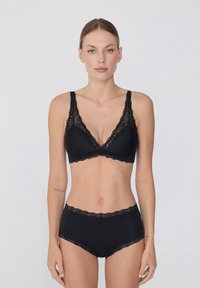 Czarna koronkowa braletka z dekoltem w kształcie litery V, szerokimi ramiączkami i falbaniastymi krawędziami, w połączeniu z pasującymi, czarnymi majtkami o wysokim stanie z koronkowym wykończeniem.