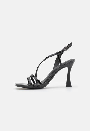 Black patent leather high-heeled sandal with three thin front straps, a curved ankle strap with a buckle, and a flared heel on a white background.