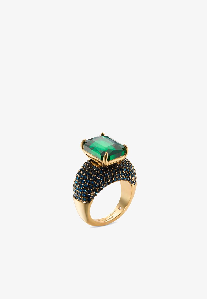 Gouden ring met een grote smaragdgeslepen groene edelsteen, geplaatst op een gestructureerde band versierd met blauwe stenen. Uniek ontwerp met gepolijste accenten.