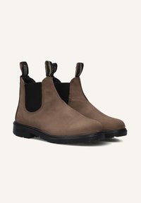 Bottines en daim marron avec panneaux latéraux élastiques, languettes pour tirer, et semelles en caoutchouc durables. Présentent un design épuré et minimaliste avec des détails cousus.